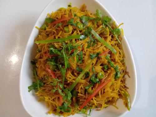 a white plate of food with noodles and vegetables at Highland Village Resort in Dharmsala