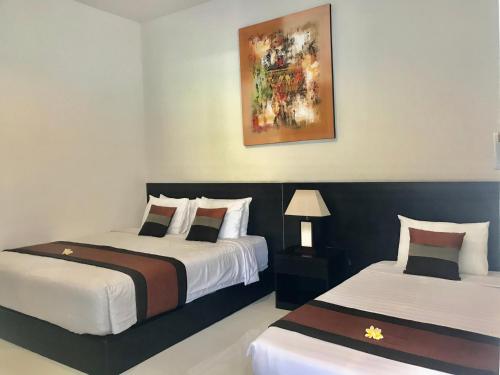 a bedroom with two beds and a painting on the wall at The Celuk Homestay in Jimbaran