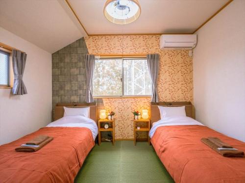 two beds in a small room with a window at Katsushika Takasago House in Tokyo