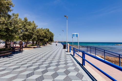 a sidewalk next to the beach with the ocean at Rambla 43 in Alicante