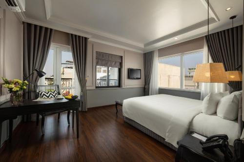 a bedroom with a bed and a desk and windows at Imperial Hotel & Spa in Hanoi