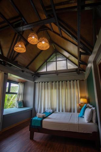 a large bed in a room with two windows at La Estancia Busuanga in Busuanga