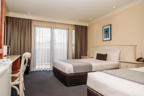 Habitación de hotel con 2 camas y escritorio en Kobbers Motor Inn en Dalby