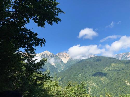 a view of a mountain range with clouds in the sky at Pension Razteca in Hakuba