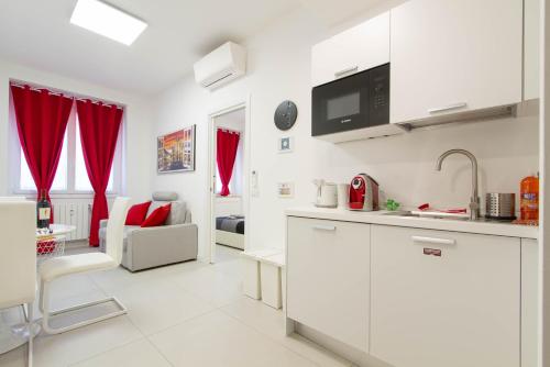 a kitchen with white cabinets and red curtains at Metro Plaza Apartment -Buenos Aires in Milan