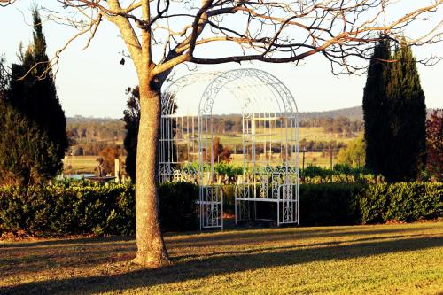a glass greenhouse in a park with a tree at Blueberry Hill Vineyard Stay in Rothbury