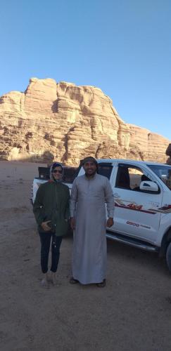 two men standing in front of a vehicle in the desert at Bronze Mountains Camp Wadi Rum in Aqaba