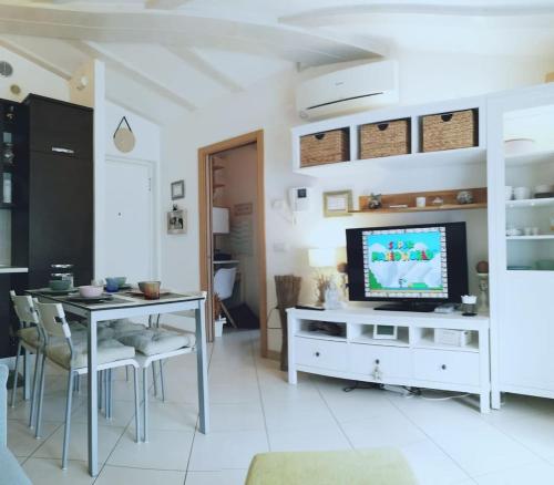 Il comprend un salon doté d'une télévision et d'une table avec des chaises. dans l'établissement Appartamento Olea, à Arco