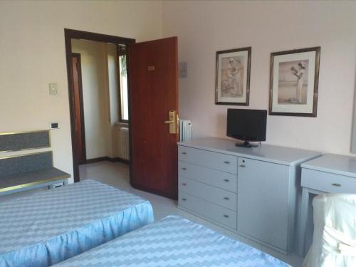 a bedroom with two beds and a dresser with a television at Grand Hotel Fagiano Palace in Formia