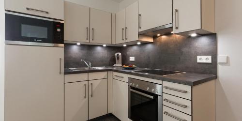 a kitchen with white cabinets and a sink at Boardinghouse E68 in Schliengen