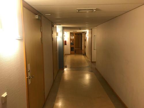 an empty hallway with a long corridor with doors and a long hallway at Nattvikens Vandrarhem in Härnösand