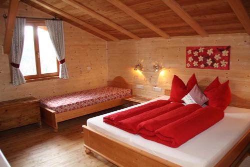 a bedroom with a bed with red sheets and a window at Neu-Schötzerhof in Meltina