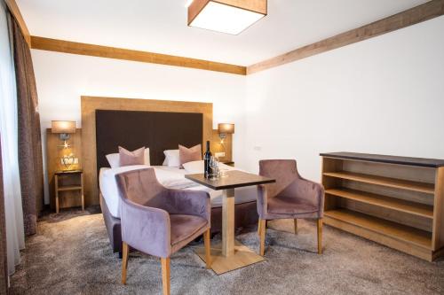 Schlafzimmer mit einem Bett, einem Tisch und Stühlen in der Unterkunft Hotel St. Nikolaus in Ischgl