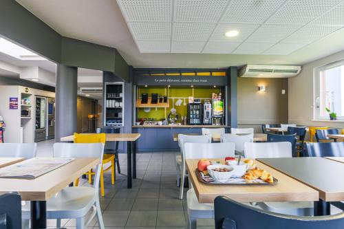 un restaurant avec des tables, des chaises et un comptoir dans l'établissement B&B HOTEL Metz Semécourt, à Semécourt