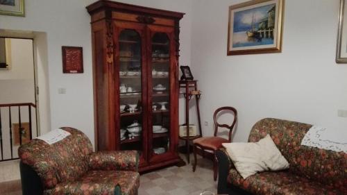 a living room with two chairs and a china cabinet at B&B ERMINIA in Laino Borgo