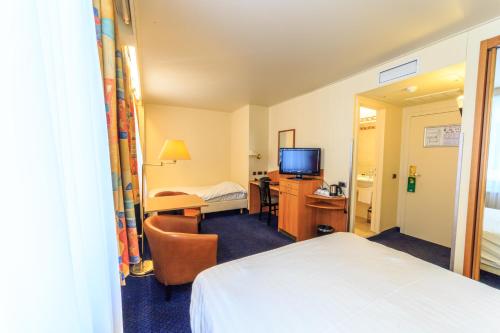 a hotel room with a bed and a desk and a television at Hotel Pacific in Ostend