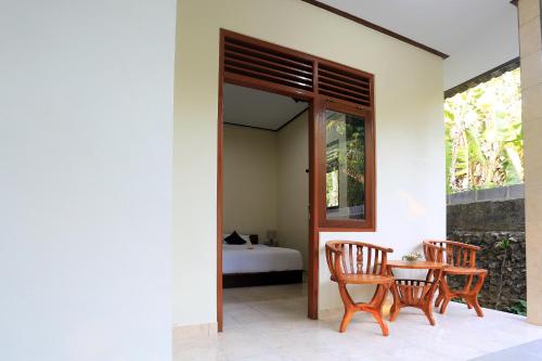 un patio con 2 sillas, una mesa y una cama en Manda Homestay, en Sanur