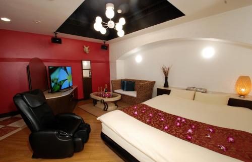 a bedroom with a bed and a chair and a television at Comfort Hotel Hu in Koshigaya