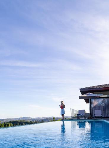 a woman standing on the edge of a swimming pool at Collection Luxury Accomodation Simola House in Knysna