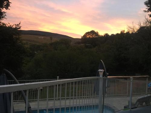a sunset over a swimming pool with a fence at Sabie Self Catering Apartments in Sabie