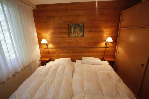 a large bed in a bedroom with wooden walls at Apartment Villa Franca in Crans-Montana