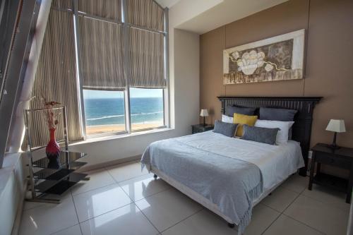 a bedroom with a bed with a view of the ocean at Stay at The Point - Prestigious Prominent Penthouse in Durban