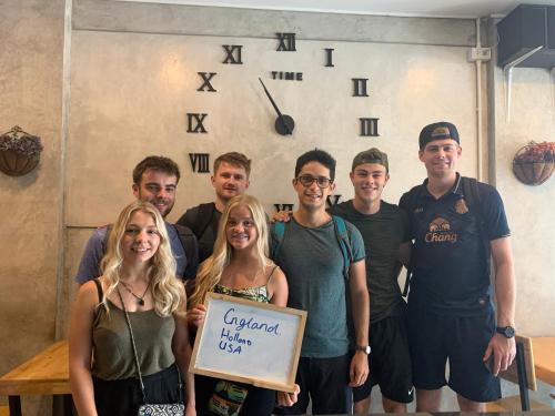 a group of people posing for a picture with a sign at Doze Hostel in Chiang Mai