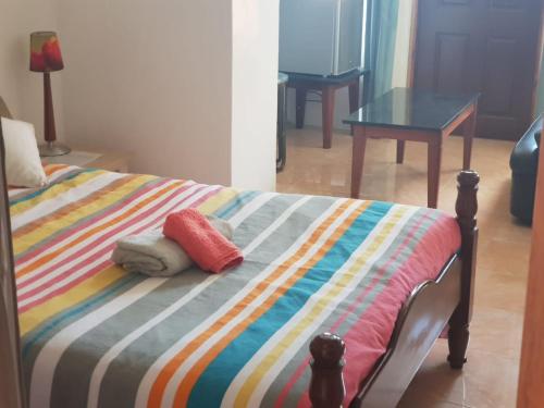 a bed with a colorful striped blanket and a table at Les Antigones in Crève Coeur