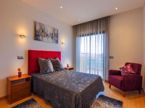 um quarto com uma cama vermelha e uma cadeira vermelha em V3, Villa Jardins Branqueira6 near Beach, Albufeira em Albufeira
