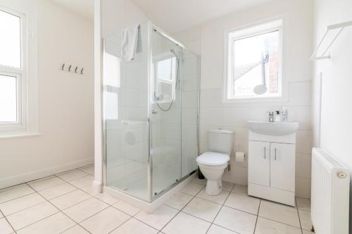 a white bathroom with a shower and a toilet at PLATFORM Fishing Quarter Apartment 2 in Hull