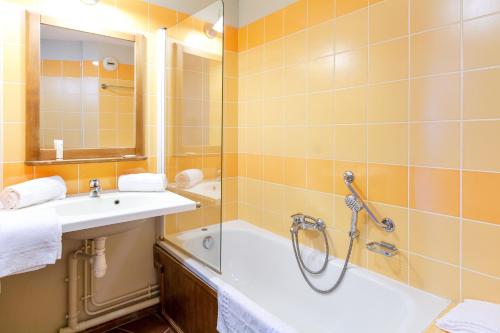 La salle de bains est pourvue d'une baignoire, d'un lavabo et d'une douche. dans l'établissement Résidence Pierre & Vacances Les Rives de la Seugne, à Jonzac