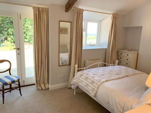 um quarto com uma cama, uma cadeira e uma janela em The View Cottage - Tennis Court - Nr Frome, Longleat em Frome