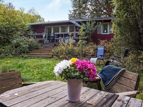 a vase of flowers on a wooden table in front of a house at 6 person holiday home in SORUNDA in Norra Svärdsö