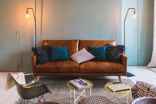a living room with a brown leather couch with pillows at L'ATELIER KEYWEEK Vintage Duplex Apartment with Parking Biarritz Center in Biarritz
