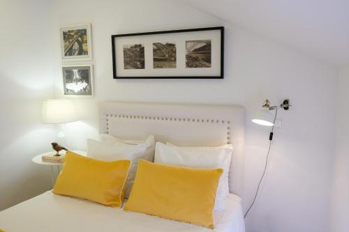 ein Schlafzimmer mit einem weißen Bett und gelben Kissen in der Unterkunft Typical Village Oporto 24 in Porto