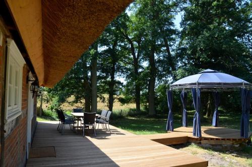 a gazebo on a porch with a table and chairs at Deichkind - Reetdachhaus direkt am Elbdeich in Mödlich