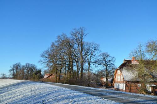 a snow covered road next to a barn at Deichkind - Reetdachhaus direkt am Elbdeich in Mödlich