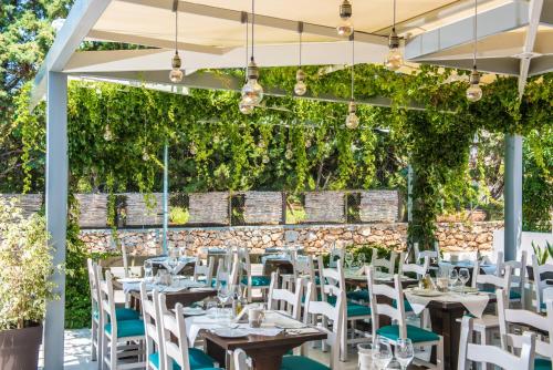 a restaurant with tables and chairs and a wall of vines at Camelot Royal Beds by Estia in Malia