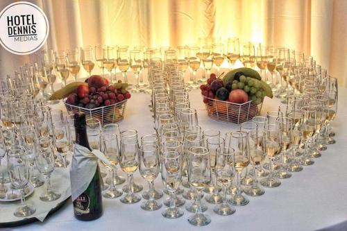 a table with wine glasses and baskets of fruit at Hotel Dennis in Mediaş
