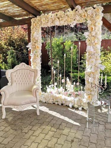 a wedding arch with flowers and a white couch at Hotel Dennis in Mediaş