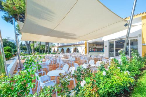un restaurante al aire libre con mesas y sillas blancas en Globales Playa Estepona, en Estepona