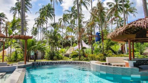a pool at a resort with palm trees in the background at Nacpan Beach Glamping Managed by H Hospitality Group in El Nido