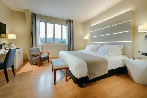 a hotel room with a large bed and a desk at Abba Euskalduna Hotel in Bilbao