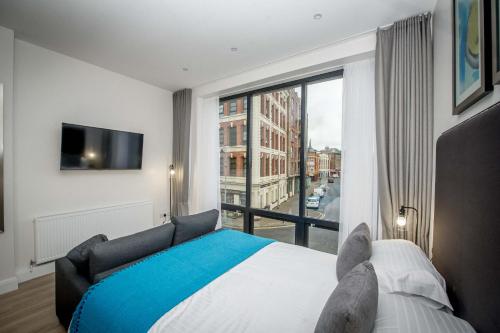 a bedroom with a bed and a large window at The James Suites in Derry Londonderry