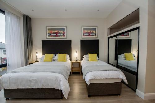 a bedroom with two beds with yellow pillows at The James Suites in Derry Londonderry