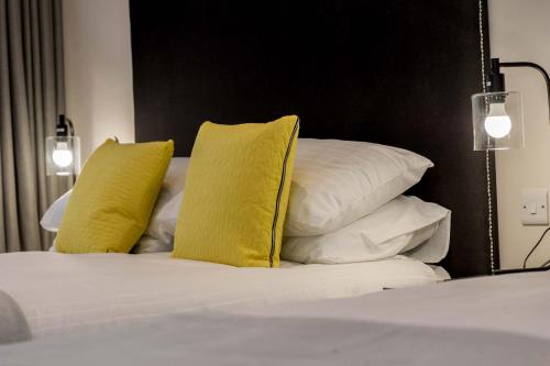 a bed with two yellow pillows on top of it at The James Suites in Derry Londonderry