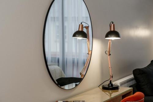 a mirror on a wall with two lamps and a chair at The James Suites in Derry Londonderry