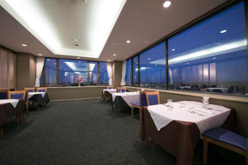 a restaurant with tables and chairs and large windows at Hotel Satsukien in Kanoya