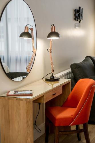 a desk with a lamp and a chair and a mirror at The James Suites in Derry Londonderry