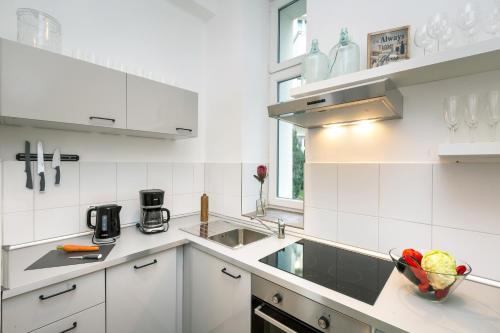 una cucina bianca con lavandino e cesto di frutta di Newton-Appartement mit 3 Schlafzimmern a Berlino